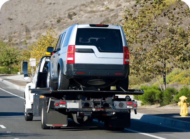 SUV being towed on a flatbed truck along a highway.