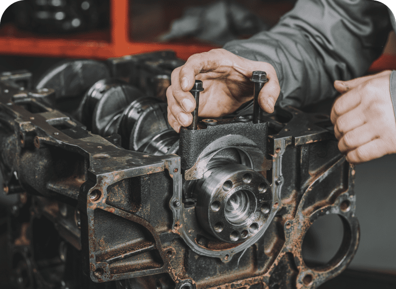 A mechanic tightening a bolt on an engine part with a wrench.