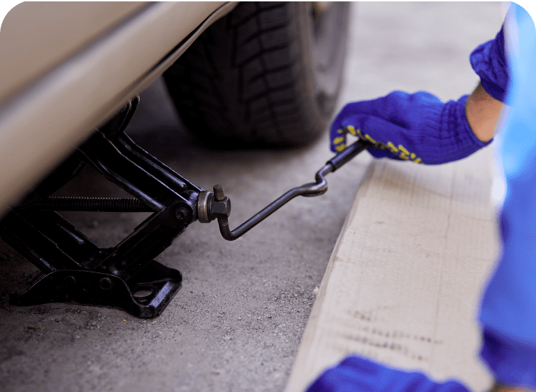 Person using a car jack to lift a vehicle for maintenance.