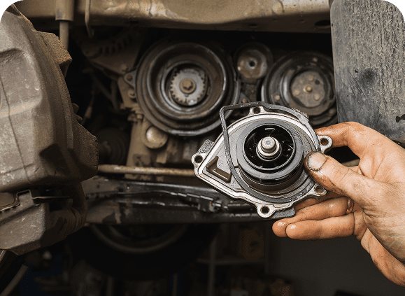 Mechanic holding car part near engine